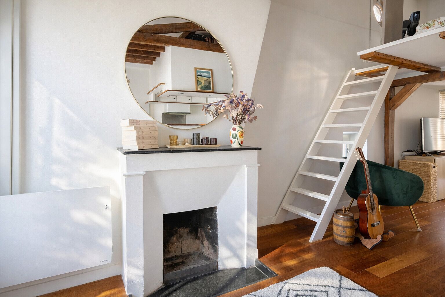 Een kamer met een witte open haard, een spiegel, een ladder en een gitaar.