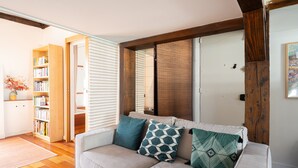 A living room with a sofa, a bookshelf, and a wooden beam structure. - Appartement Panorama Sacré-Cœur - Welkeys (Paris)