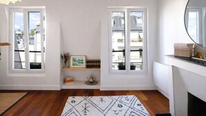 A room with two windows, a fireplace, and a rug. - Appartement Panorama Sacré-Cœur - Welkeys (Paris)