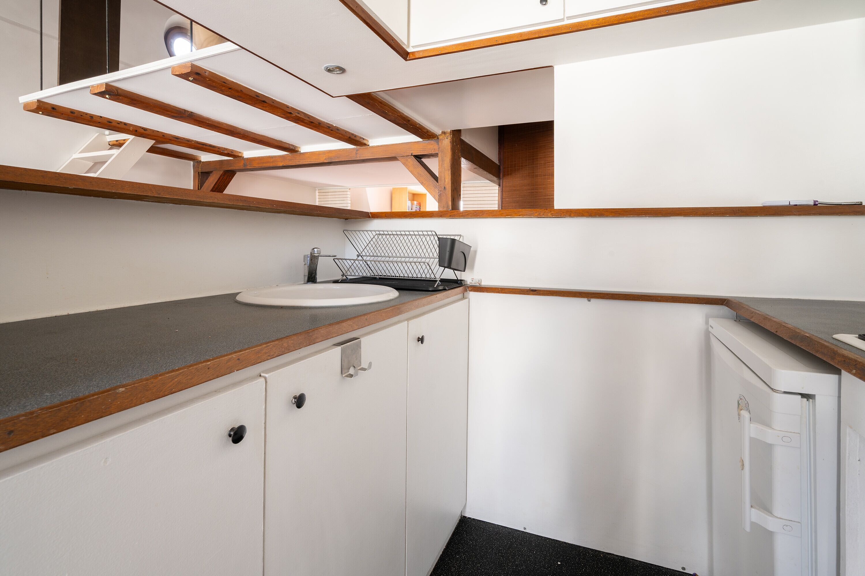 A compact kitchen with a sink, countertop, and cabinets.