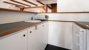A compact kitchen with a sink, countertop, and cabinets. - Appartement Panorama Sacré-Cœur - Welkeys (Paris)