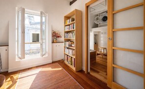 Ein Zimmer mit großem Fenster, einer Holzregal und Blick auf einen Waschraum.