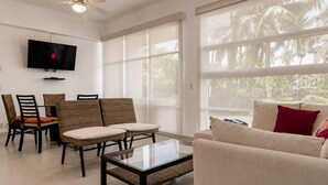 A modern living room with a glass coffee table, a sofa, and chairs.
