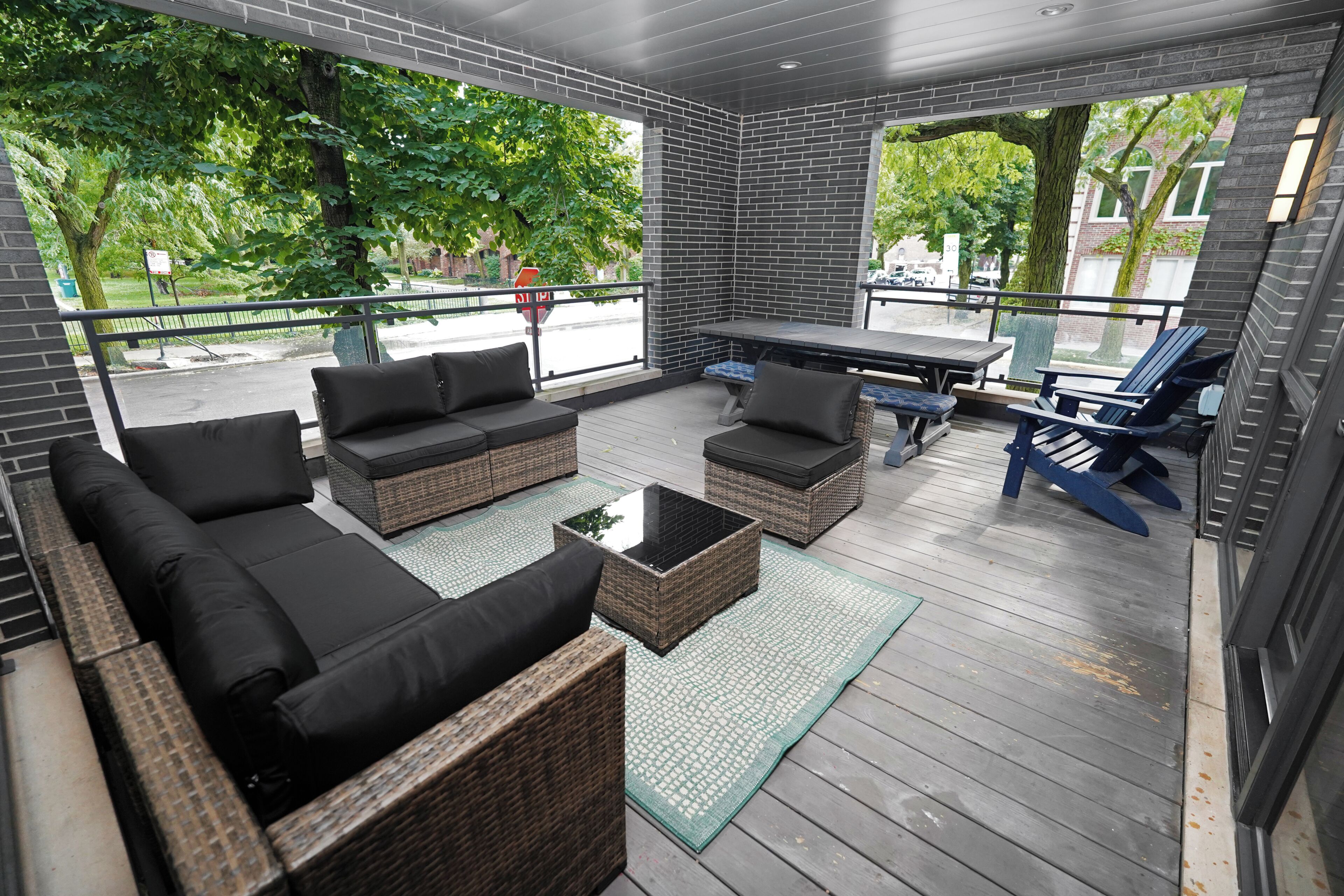 A covered outdoor seating area with wicker furniture, a table, and chairs.