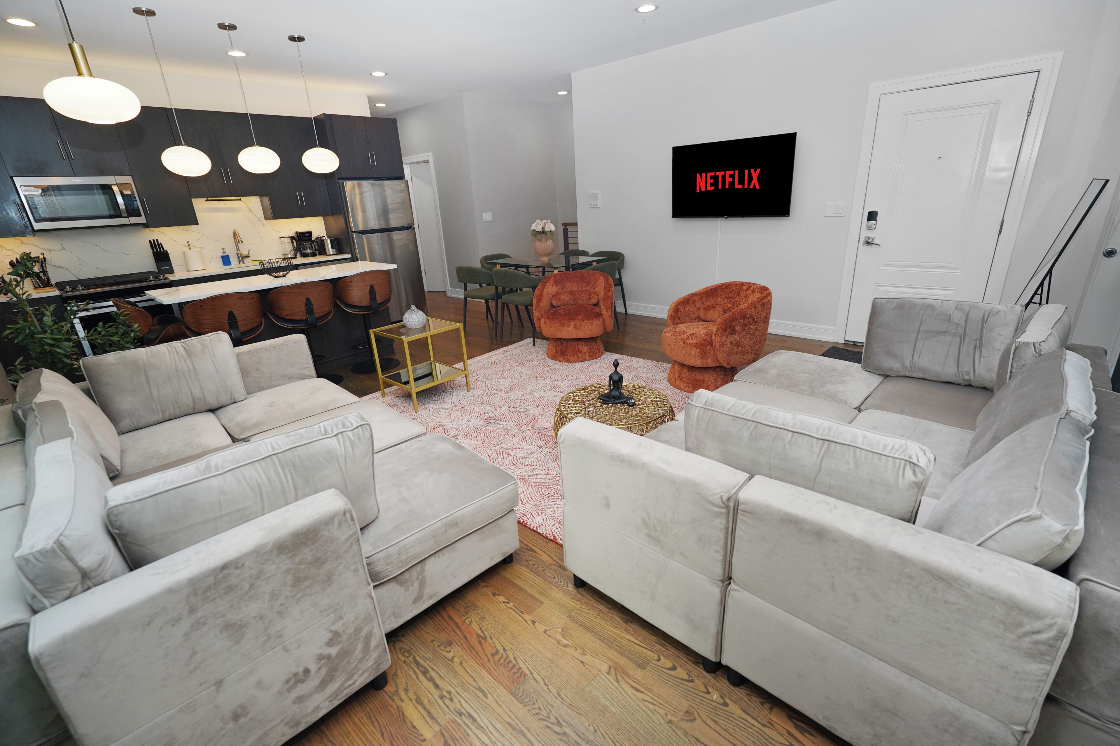 A modern living room with a grey sofa set, a coffee table, and a flat-screen TV mounted on the wall.