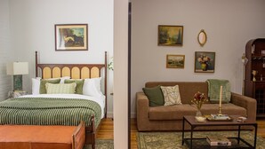A bedroom with a bed, bedside table, and a nightstand. There is a living room with a sofa, a coffee table, and a bookshelf.