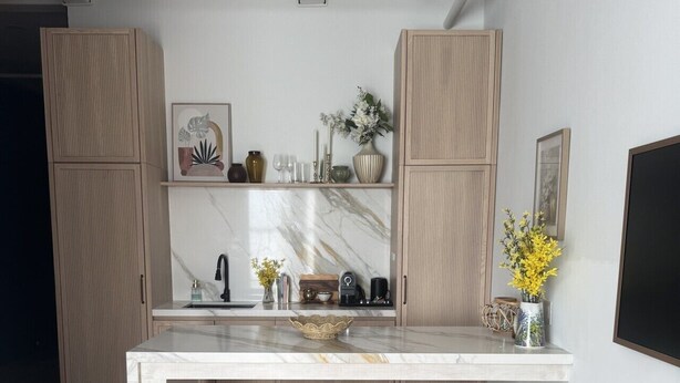 A modern kitchen with a marble countertop, wooden stools, and a built-in oven.