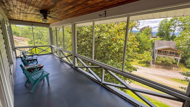 Ein überdachter Balkon mit Blick auf ein Haus und Bäume.