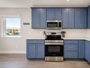 Eine moderne Küche mit blauen Schränken, einer Edelstahl-Mikrowelle und einem Frigidaire-Ofen.