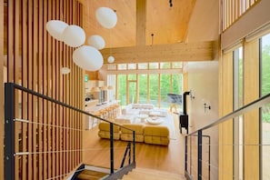 Un interior moderno con escalera, paredes de madera y ventanas amplias.