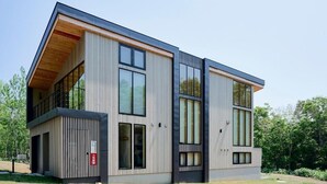 A modern two-story building with large windows, a flat roof, and a wooden sloped section. - Grand Tsuru B (Niseko)