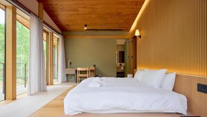 A bedroom with a large bed, wooden ceiling, and a desk with a chair. - Grand Tsuru B (Niseko)