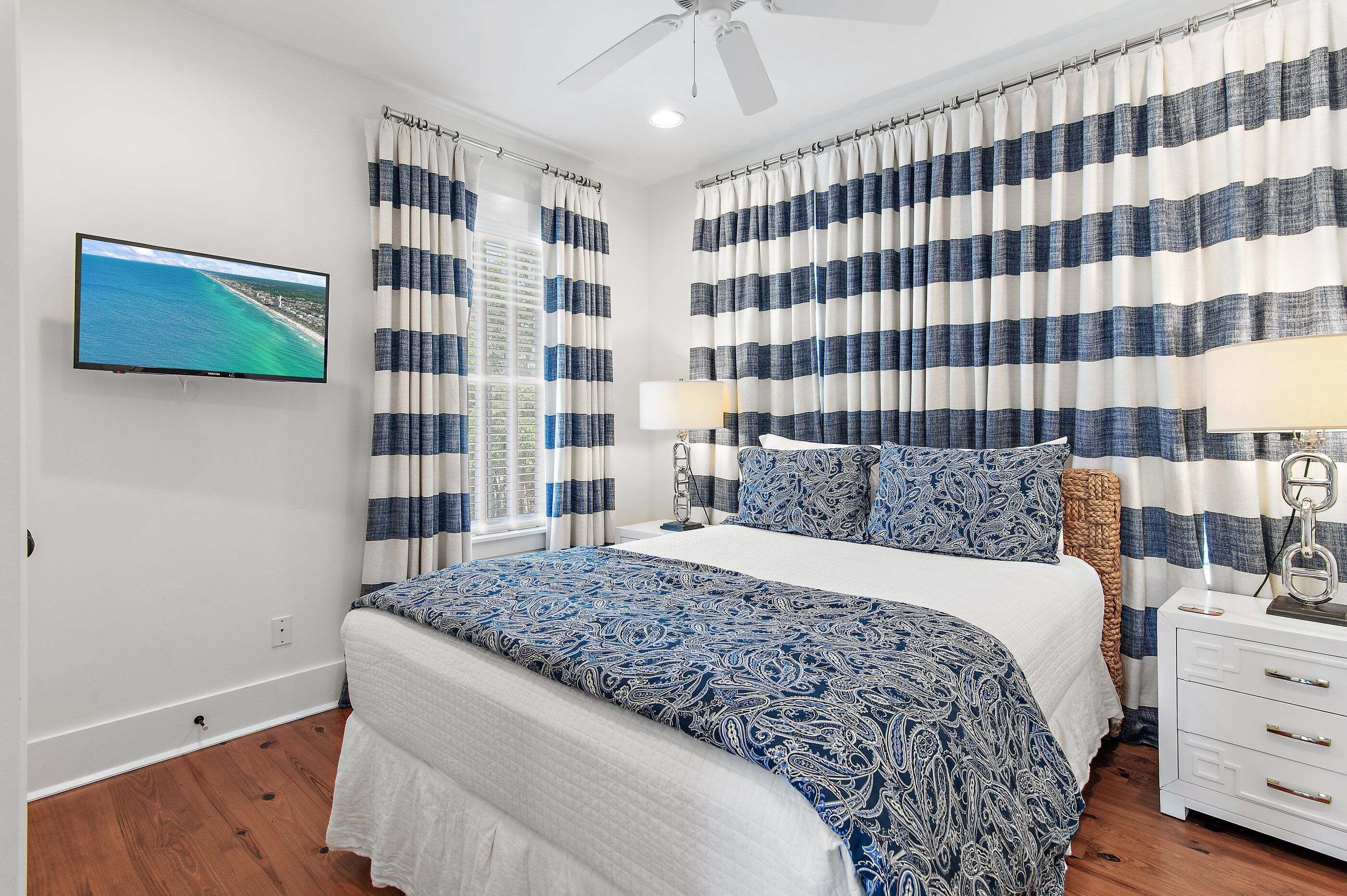 A bedroom with a bed, curtains, a television, and a nightstand.