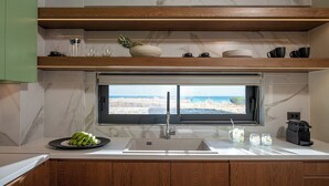 Una cocina moderna con un ventanal grande, un fregadero y una encimera con un cuenco de fruta y un plato de plátanos.