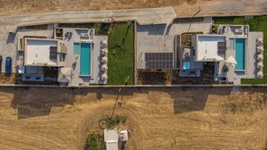 Un edificio moderno con dos piscinas, un patio cubierto y vistas a un paisaje seco y con pasto.
