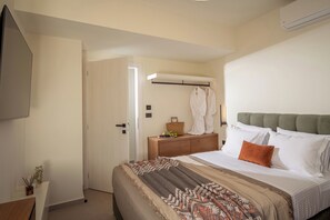 A bedroom with a bed, a bedside table, a dresser, a wall-mounted air conditioner, and a door. - Thenad Villas - Villa Theo Heated Pool, by Estia (Prinos)