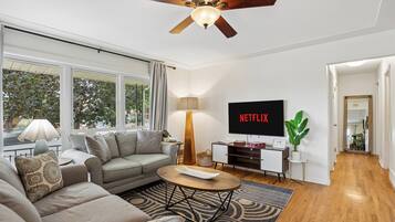 A modern living room with a grey sofa, a coffee table, a TV, and a ceiling fan.