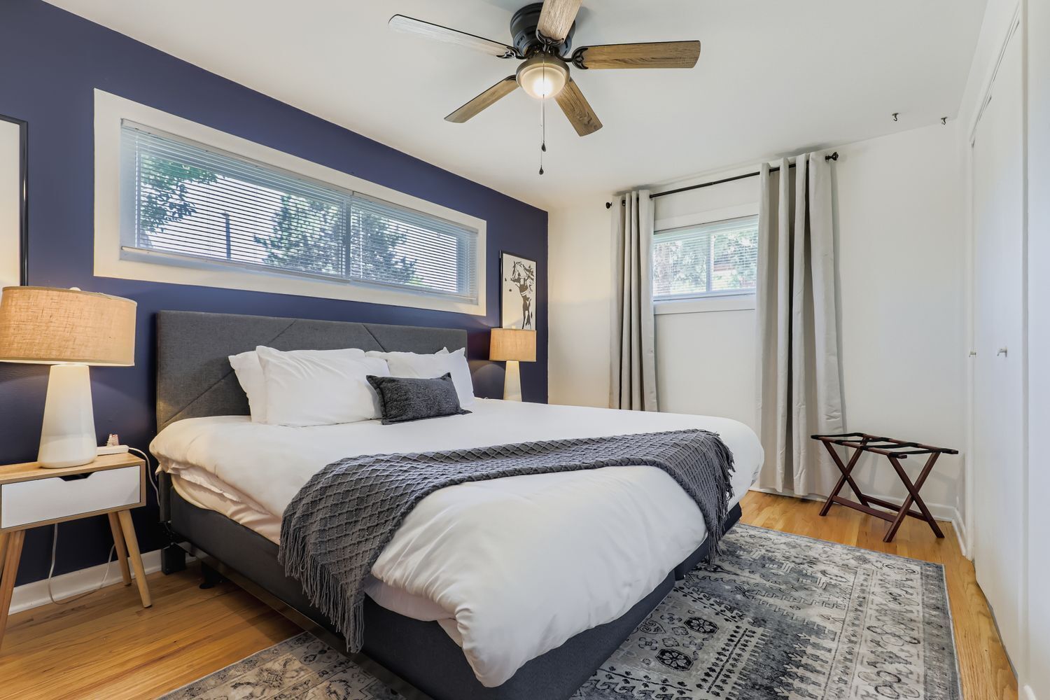 A bedroom with a bed, a nightstand, a ceiling fan, a window with blinds, and a rug.