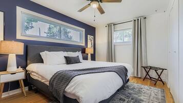 A bedroom with a bed, a nightstand, a ceiling fan, a window with blinds, and a rug.