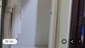 Um armário com roupas penduradas e um cobertor dobrado.