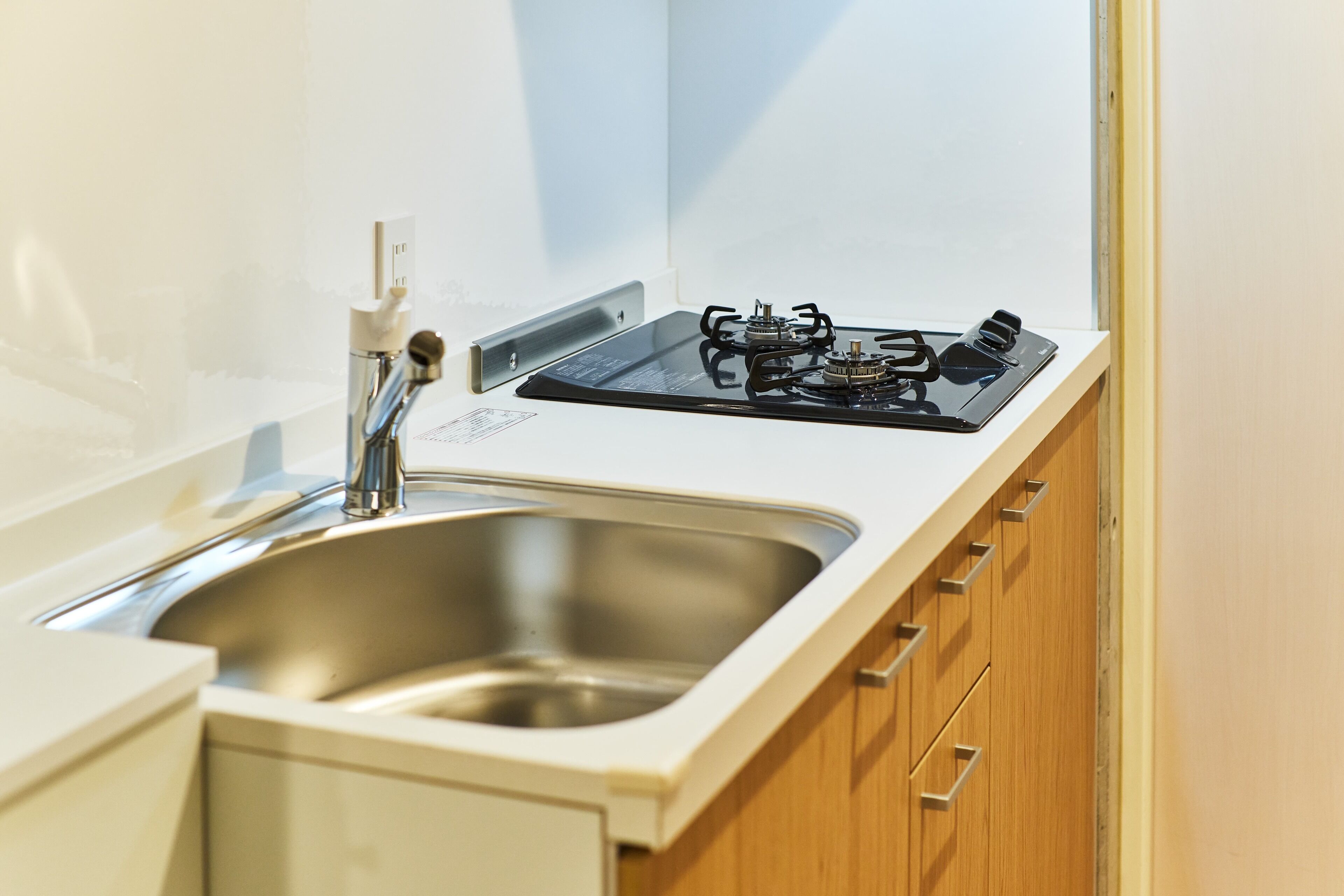A kitchen with a stainless steel sink, a gas stove, and wooden cabinets.