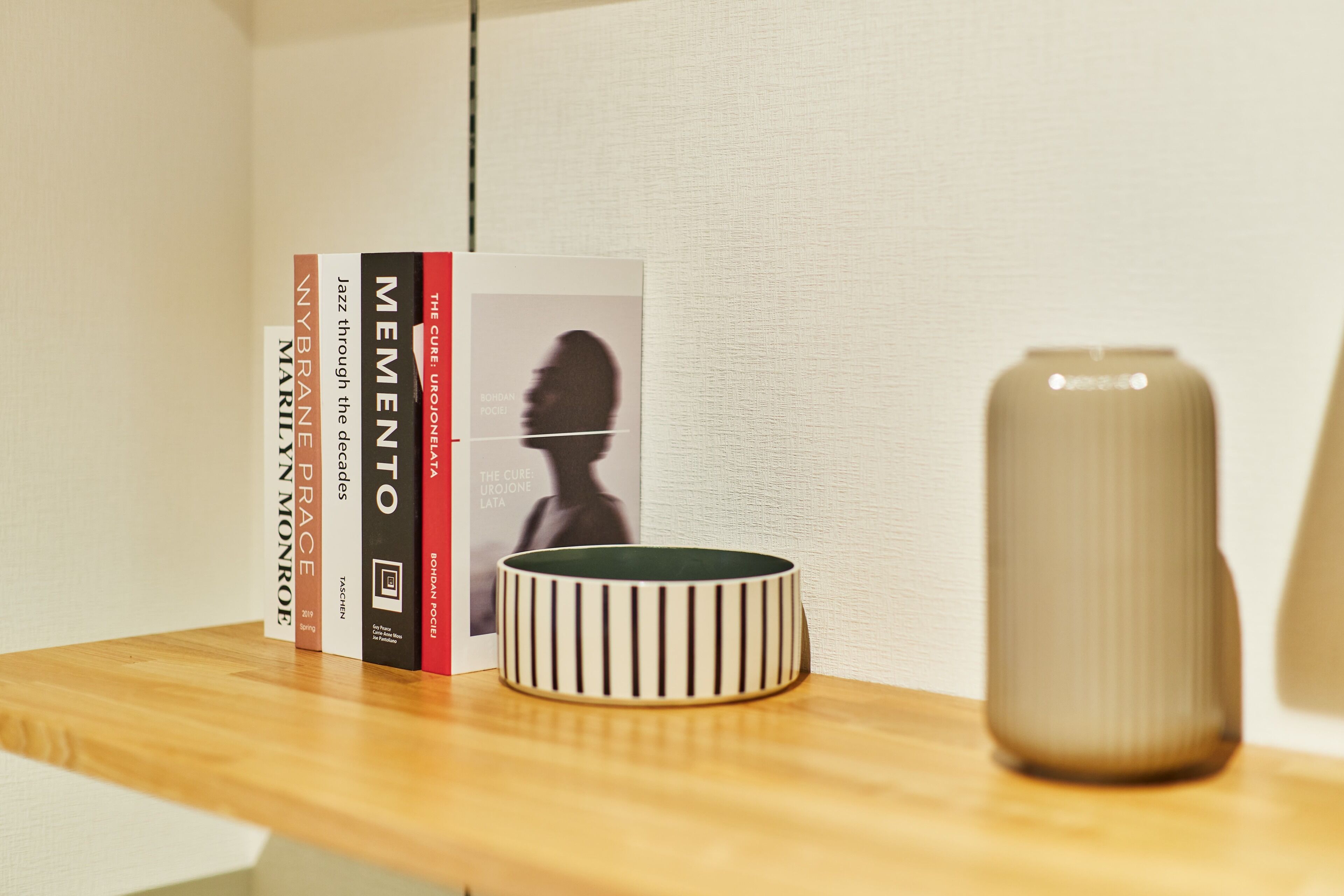 A shelf with books and a vase.