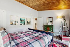 Ein Schlafzimmer mit einem Bett, einem Schminktisch, einem Spiegel und Bildern an der Wand.