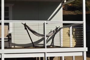 A white building with a balcony featuring two hammocks.