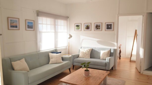 A living room with a light blue sofa, a wooden coffee table with a plant, and a grey armchair. - Mallee Drift - Exhale and Relax (James Well)