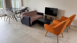 Una sala de estar moderna con un sofá, un televisor y sillones naranjas.