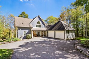 Une maison à deux étages avec un garage, une véranda et une allée menant à l’entrée.