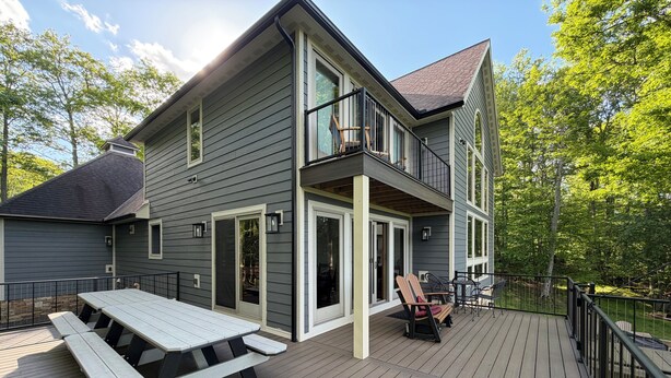 Ein zweistöckiges Haus mit einer Terrasse und einem überdachten Patio, sowie einem großen Fenster.