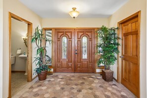 A hallway with a wooden door, a potted plant, and a tiled floor. - Mountaintop retreat with 5 bedrooms, hot tub, pool table, and community pool! (McHenry)
