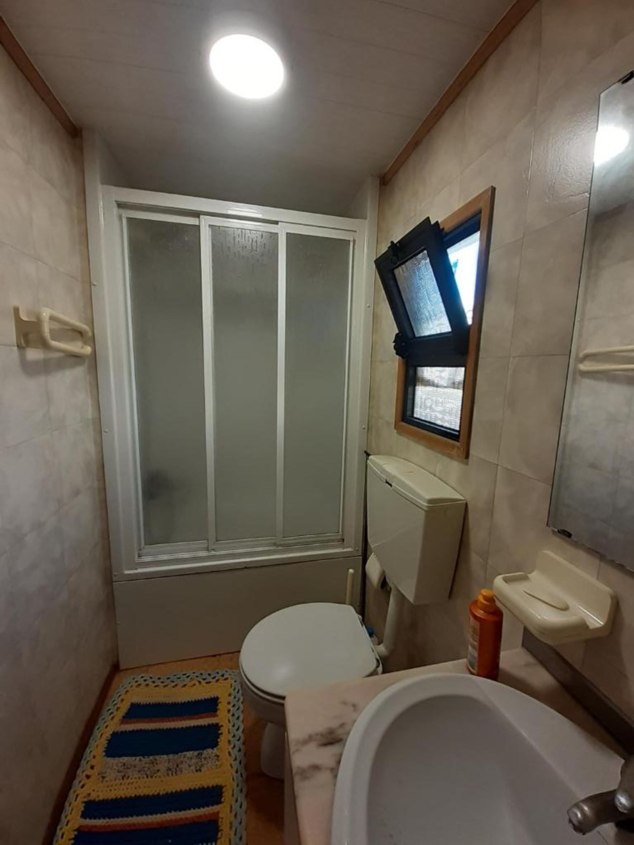 Une petite salle de bain comprenant des toilettes, un lavabo, une baignoire, une fenêtre et une douche.