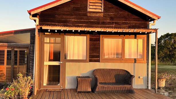 Eine Holzhütte mit Veranda, einer Schiebetür und einem Korbsessel.