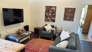 Ein Wohnzimmer mit einer Couch, einem Fernseher, einem Holztisch und einem roten Teppich.