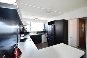 A compact kitchen with a microwave, stove, refrigerator, and dishwasher. - A Comfortable Base for your Twizel Adventure (Twizel)