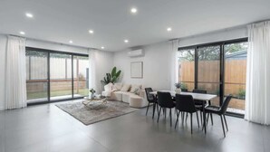 Amplia sala de estar con comedor, ventanas grandes y puerta corrediza de vidrio que da a un patio trasero.