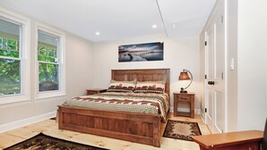 Una camera da letto con un letto di legno, un comodino, una lampada e un quadro appeso al muro.