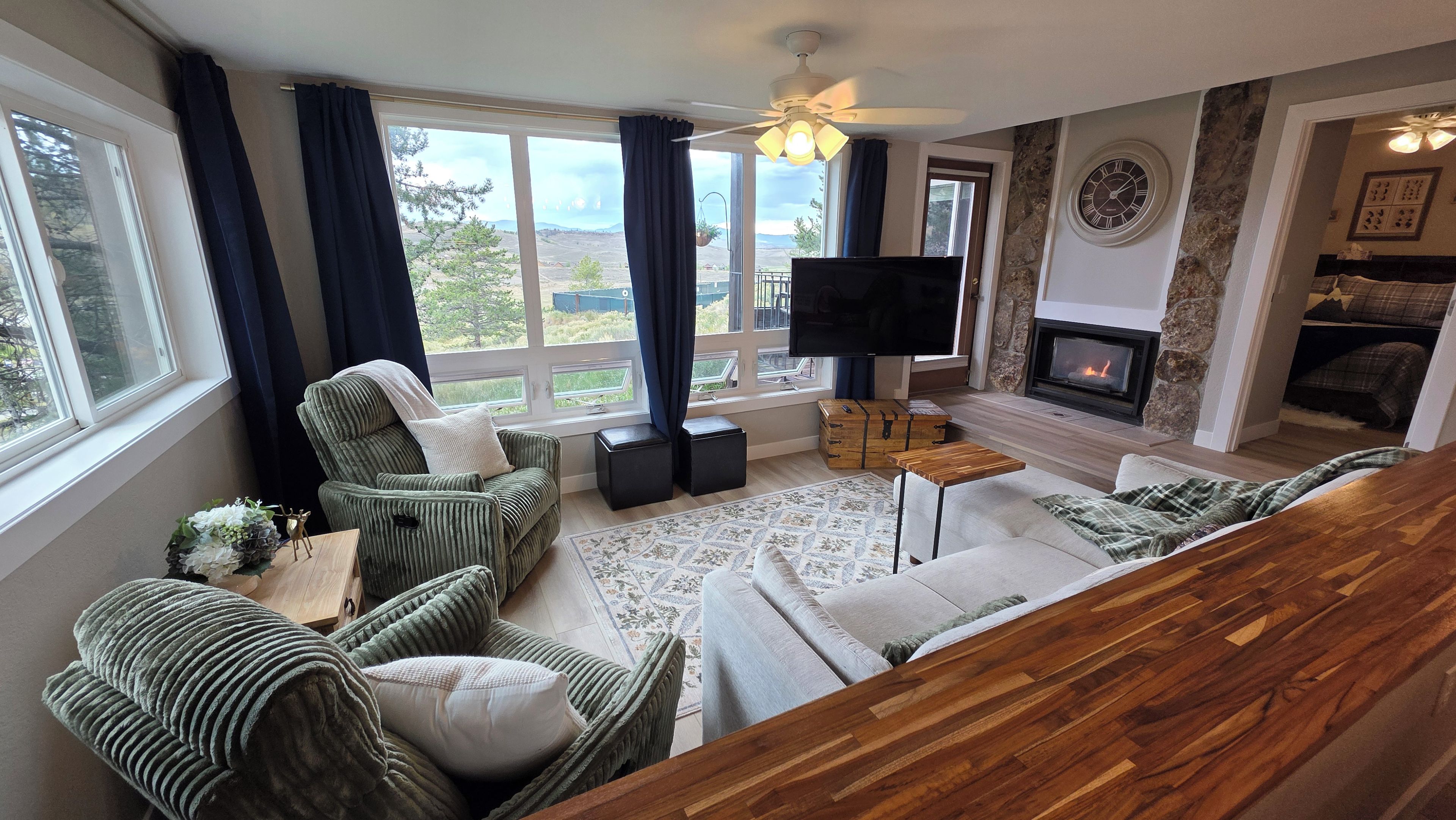 Una sala de estar con chimenea, televisor y vistas al exterior.