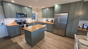 A modern kitchen with grey cabinets, stainless steel appliances, and a wooden island. - New Listing! True ski-in/out newly remodeled all-four seasons mountainside condo (Granby)