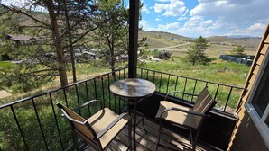 A balcony with a table and chairs, overlooking a grassy landscape with houses and trees. - New Listing! True ski-in/out newly remodeled all-four seasons mountainside condo (Granby)