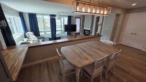 A modern kitchen with a wooden countertop, a dining table with chairs, a built-in TV, and a stone fireplace. - New Listing! True ski-in/out newly remodeled all-four seasons mountainside condo (Granby)