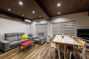 A modern living room with a sofa, armchair, dining table, and chairs.