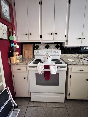 A kitchen with white cabinets, a stove, and a microwave. - Walk to Historic Oxford Square, 3BR/3BA Near Ole Miss, Peaceful Garden Retreat (Oxford)