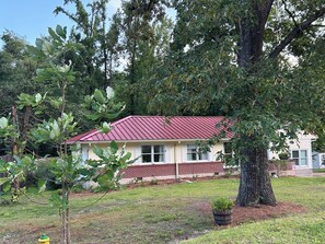 A house with a red roof, surrounded by trees and a grassy yard. - Walk to Historic Oxford Square, 3BR/3BA Near Ole Miss, Peaceful Garden Retreat (Oxford)