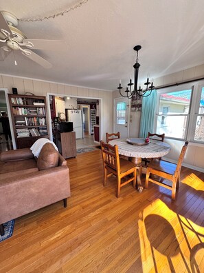 A spacious living room with a wooden floor, a dining table with chairs, a sofa, and a ceiling fan. - Walk to Historic Oxford Square, 3BR/3BA Near Ole Miss, Peaceful Garden Retreat (Oxford)