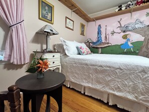 A bedroom with a bed, a nightstand, a lamp, a wall with a painting, and a window with curtains. - Walk to Historic Oxford Square, 3BR/3BA Near Ole Miss, Peaceful Garden Retreat (Oxford)