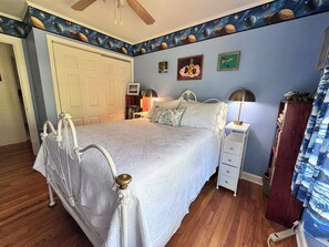 Ein Schlafzimmer mit Bett, Nachttischen, Kleiderschrank und Deckenventilator.