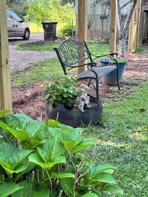 A garden area with a bench, a statue, and a potted plant.